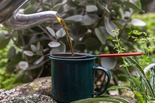 Teapot pouring tea into mug with filter