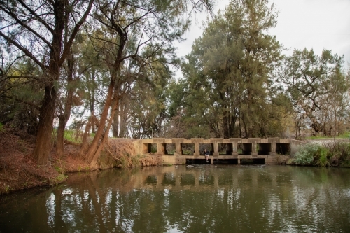 Teen boy sitting under low bridge over the Cudgegong River in rural New South Wales - Australian Stock Image