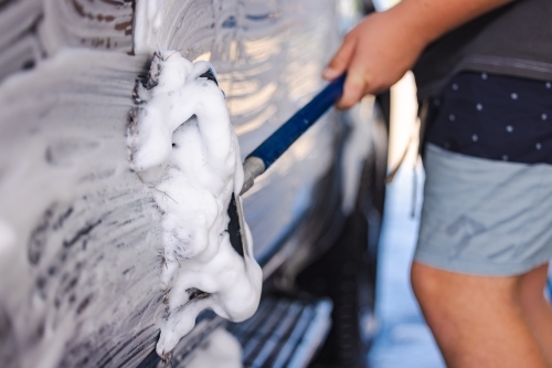 Teen boy washing vehicle in self-service car wash bay - Australian Stock Image