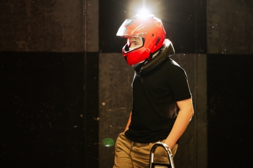 Teen boy with red helmet standing among Go Karts getting ready to race - Australian Stock Image