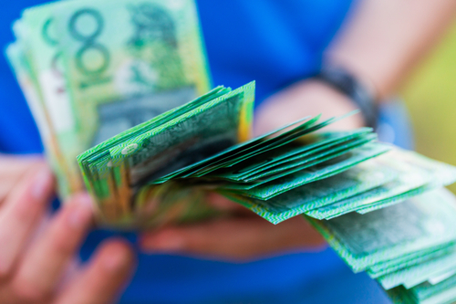 Teen child holding hundreds of dollars of Australian cash educations savings and expenses - Australian Stock Image