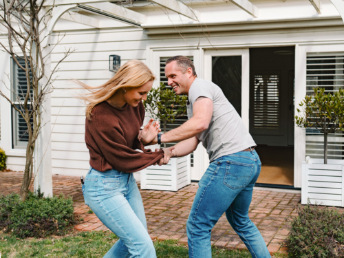 teen daughter and dad playing together outside suburban house entrance - Australian Stock Image