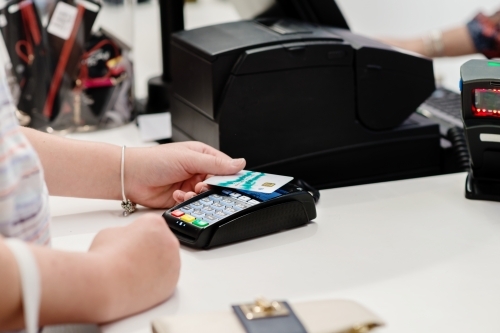 teen girl at the cash register, paying with debit card - Australian Stock Image