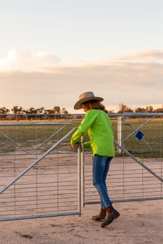 Teen girl closing farm gate - Australian Stock Image