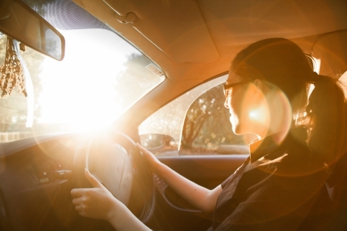 Teen girl driving car with lens flare