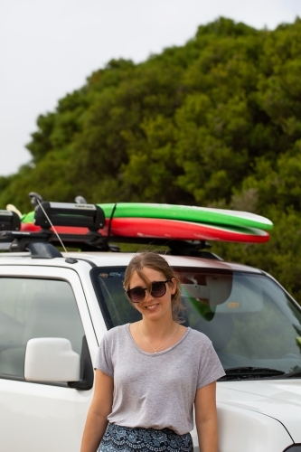 Teen Girl Leaning Against Suv With Surfboards On Roof Rack Teen Girl Leaning Against Suv With Surfboards On Roof Rack