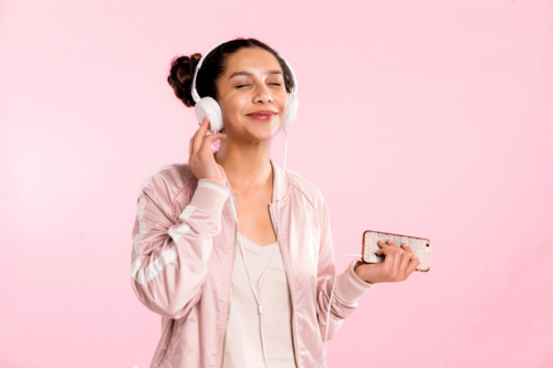 teen girl pin pink listening to music with headphones in studio - Australian Stock Image