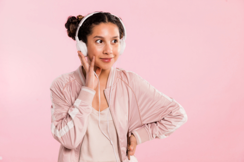 teen girl pin pink listening to music with headphones in studio - Australian Stock Image