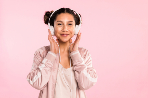 teen girl pin pink listening to music with headphones in studio - Australian Stock Image