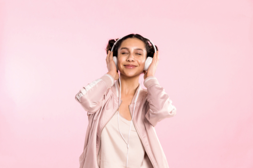 teen girl pin pink listening to music with headphones in studio - Australian Stock Image