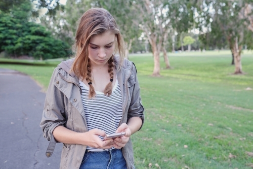 Teen girl using mobile phone while walking in the park