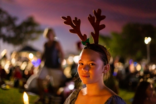 teen girl wearing antler headdress at christmas carols - Australian Stock Image