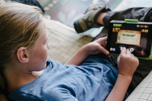 teen girl with iPad on sofa - Australian Stock Image