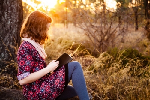 Teen girl with notebook and short hair at sunset - Australian Stock Image