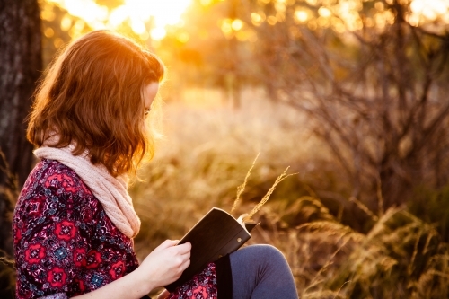 Teen girl with notebook and short hair at sunset - Australian Stock Image