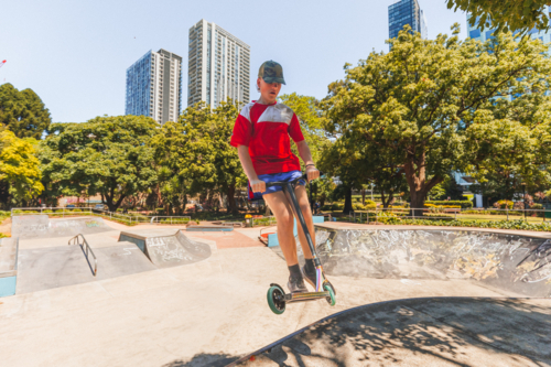 Teenage boy riding scooter on ramps at skate park - Australian Stock Image
