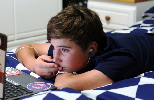 Teenage boy studying on laptop
