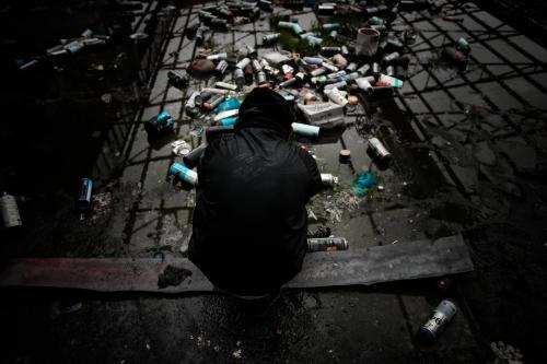 Teenage boy surrounded by empty spray cans in deserted warehouse