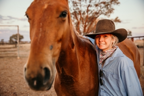 Teenage female smiling beside brown horse - Australian Stock Image