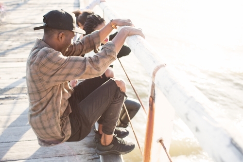 Teenage friends relaxing on a jetty - Australian Stock Image