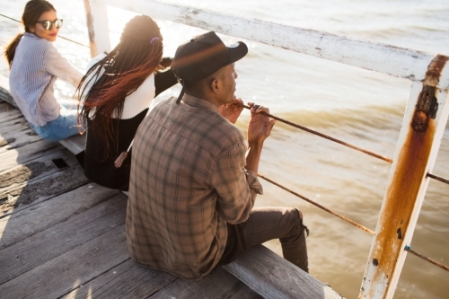 Teenage friends relaxing on a jetty - Australian Stock Image
