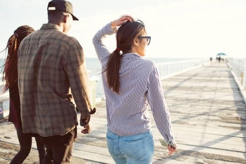 Teenage friends walking along a jetty - Australian Stock Image