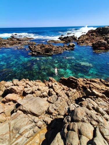 Teenage girl floating in an ocean rock pool - Australian Stock Image