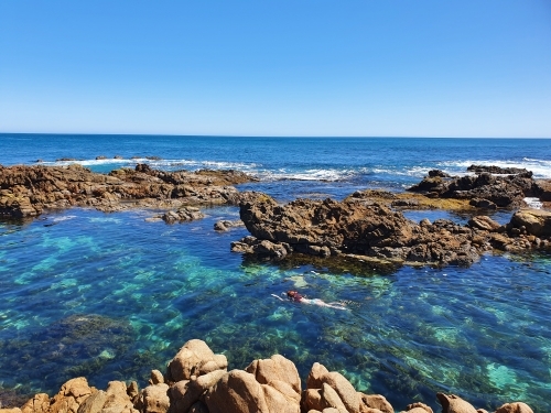 Teenage girl floating in an ocean rock pool - Australian Stock Image