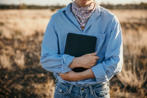 Teenage girl holding her laptop in paddock - Australian Stock Image
