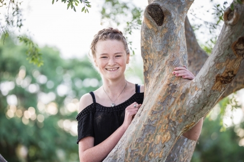 Teenage girl laughing climbing a tree - Australian Stock Image