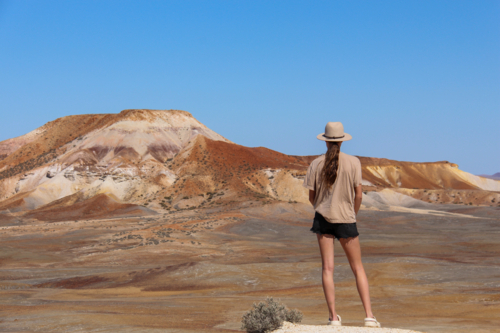 Teenage girl looking out on colourful desert hills - Australian Stock Image