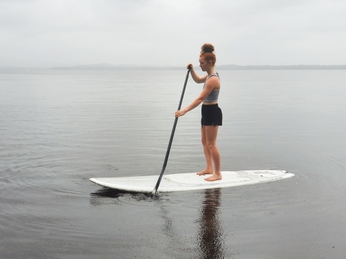 Teenage girl on a stand up paddle board - Australian Stock Image
