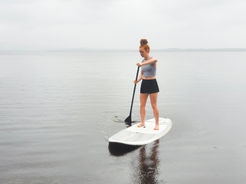 Teenage girl on a stand up paddle board - Australian Stock Image