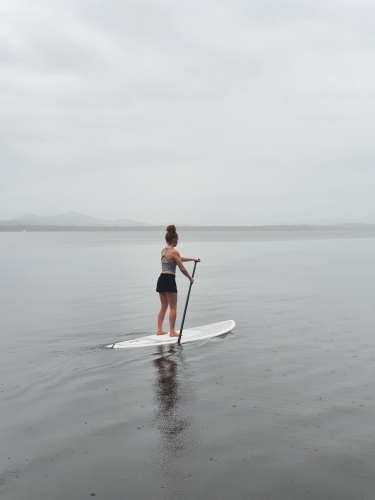 Teenage girl on a stand up paddle board - Australian Stock Image