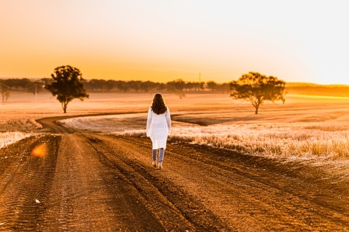 Teenage girl walking away from the camera on dirt road