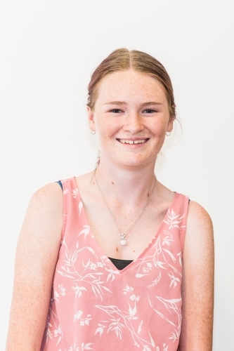 Teenage girl wearing necklace smiling white background - Australian Stock Image