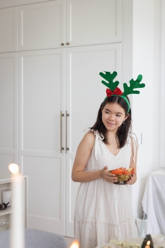 Teenage girl wearing reindeer antlers holding bowl of prawns - Australian Stock Image