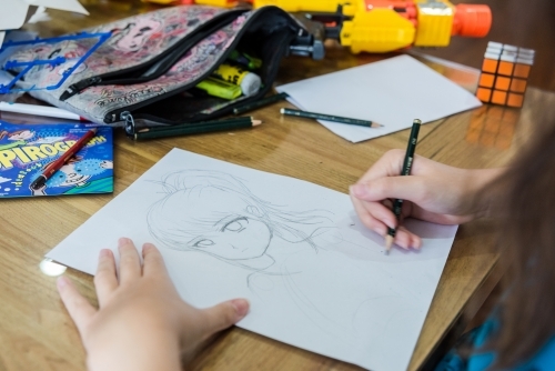 Teenage girls drawing Manga artwork in pencil - Australian Stock Image