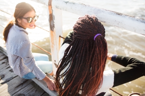 Teenage girls relaxing on a jetty - Australian Stock Image