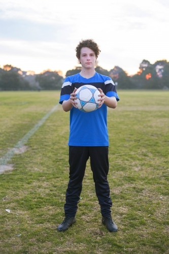 Teenage soccer player on a soccer pitch with ball.