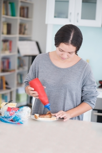 Teenager having sausage on bread with tomato sauce - Australian Stock Image