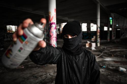 Teenager holding spray paint can in disused warehouse - Australian Stock Image