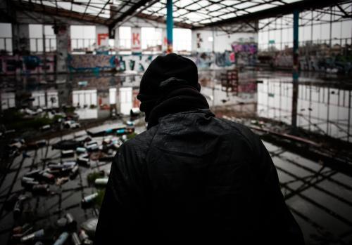 Teenager in disused warehouse surrounded in empty spray cans