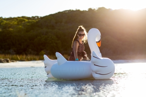 Teenager in the water with a giant inflatable swan