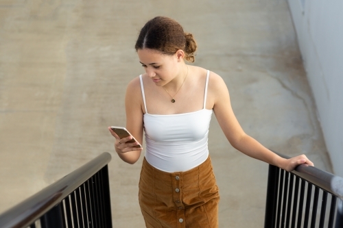 Teenager looking at phone on staircase - Australian Stock Image