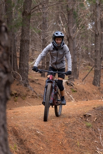 teenager riding mountain bike through the pine forest