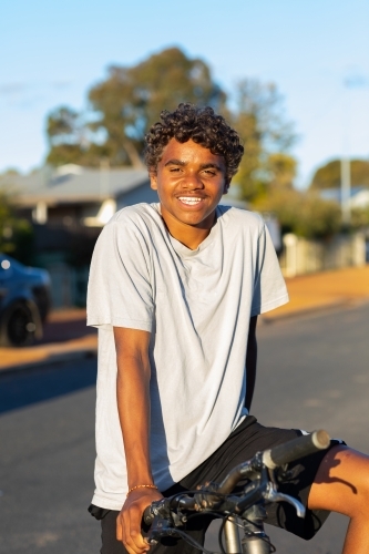 Teenager smiling while resting on bicycle - Australian Stock Image