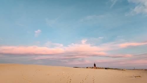 Teenager standing on the sand dunes at Birubi Beach at sunset - Australian Stock Image