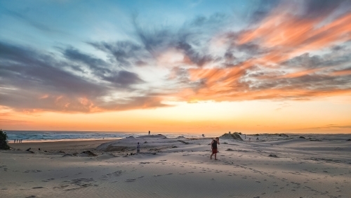 Teenager walking on the sand dunes at Birubi Beach at sunset - Australian Stock Image