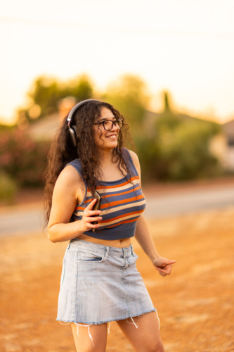 teenager with headphones dancing to music outside at sunset - Australian Stock Image